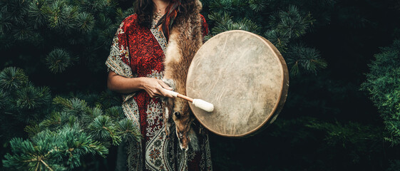 shamanic girl playing on shaman frame drum in the nature.