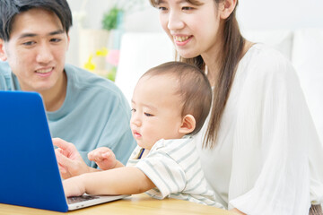 Fototapeta na wymiar 両親と赤ちゃん　ノートパソコン　リビング