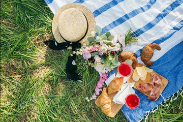 Picnic in the Park on the green grass with berry, croissants, juice, bouquet, hat. Picnic blanket. Summer holiday