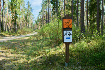 Szlak rowerowy ścieżką leśną. Oznakowanie trasy rowerowej. Mała głębia ostrości, bokeh, f/1,4. Zieleń, błękit, wiosna.