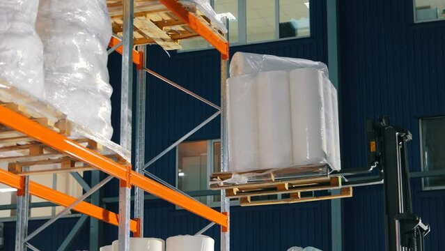 Agrofibre put on the shelf of the warehouse. The forklift puts the goods on the shelves of the warehouse. warehouse work.