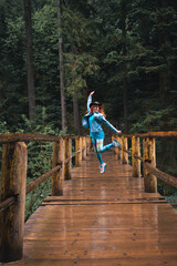 Woman Traveler with leather hat hiking on bridge over river Travel Lifestyle concept forest on background Summer journey vacations outdoor. Vertical photo