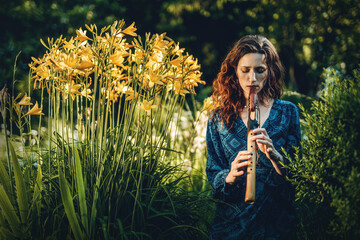beautiful shamanic girl playing on indian flute in the nature. © jozefklopacka