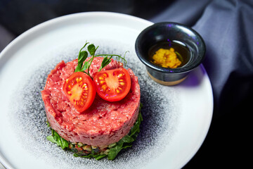 Veal tartare with Tomatoes on a white plate in a restaurant