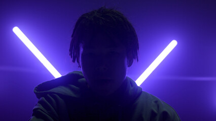 Silhouette man posing illuminated ultraviolet lamps. Dreads guy wiping face.