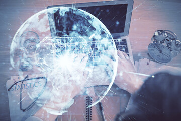 Double exposure of man's hands typing over computer keyboard and business theme hologram drawing. Top view. Financial markets concept.