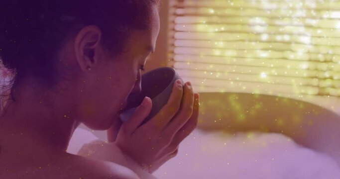 Animation of light spots over caucasian woman drinking coffee and taking bath