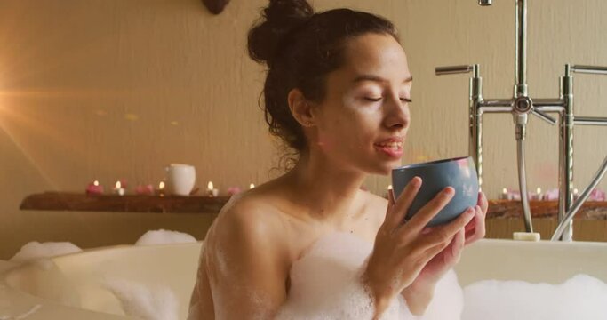 Animation of light spots over caucasian woman drinking coffee and taking bath