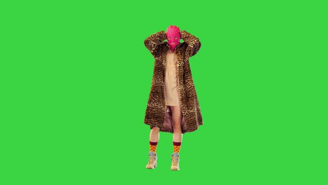 Young girl in pink balaclava and leopard coat dancing slightly on a Green Screen, Chroma Key.