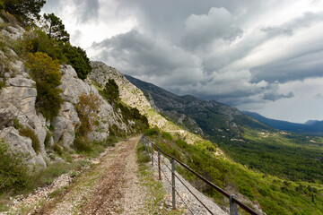 Naklejka na ściany i meble Turist's pathway based in Konavle region near Dubrovnik. The road along the slope of the mountain above the valley.