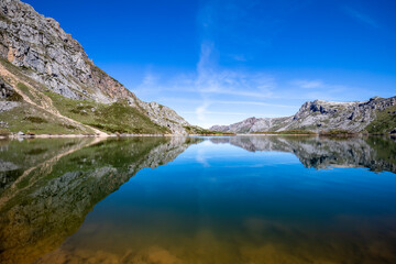 Fototapeta na wymiar Lago del Valle in the Somiedo Natural Park in Asturias, Spain. A dream environment where the mountains are reflected in the lake like a mirror. Nature in its purest state for hiking and tourism.