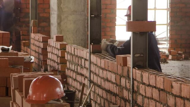 Bricklayers laying bricks to make a walls timelapse. Professional construction worker laying bricks and building inside in industrial site. Adjusting bricks by workers in uniform