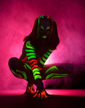Anonymous naked lady with bright fluorescent body art on stage