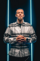 Bearded man portrait in plaid shirt with black neon background