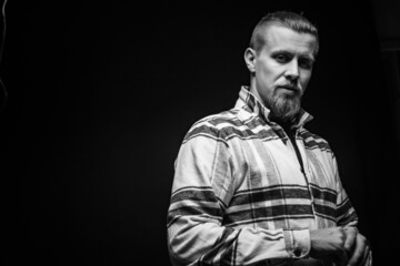 Black and white male portrait in plaid shirt on black background