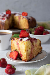 Charlotte pie strawberries with a cut piece and also cup of coffee on light gray table