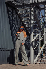 Girl in suit and glasses with beautiful smile in city. Girl on background of an iron gray staircase