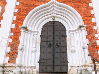 Fototapeta premium EIron doors in an ancient red brick temple. Metal dark gates of the church. Entrance to the old cathedral.