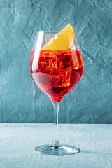 Aperol cocktail with a fresh orange, a side view on a blue background, Italian summer cold drink