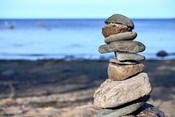 Fototapeta na wymiar Piles of gray stones are stacked in a Zen pyramid on the Baltic Sea coast for close-up meditation. Rest, meditation, tranquility, balance on the beach of the sea in summer. 