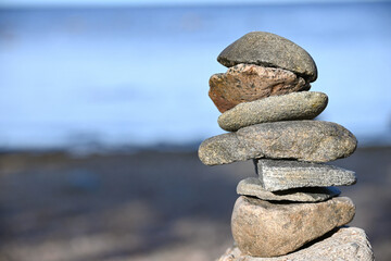 Piles of gray stones are stacked in a Zen pyramid on the Baltic Sea coast for close-up meditation. Rest, meditation, tranquility, balance on the beach of the sea in summer. 