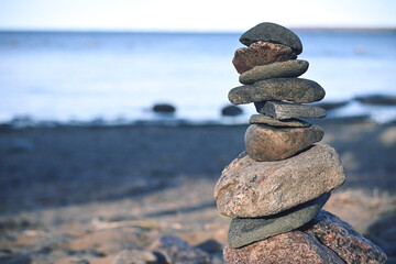 Piles of gray stones are stacked in a Zen pyramid on the Baltic Sea coast for close-up meditation. Rest, meditation, tranquility, balance on the beach of the sea in summer. 