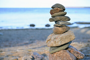 Fototapeta na wymiar Piles of gray stones are stacked in a Zen pyramid on the Baltic Sea coast for close-up meditation. Rest, meditation, tranquility, balance on the beach of the sea in summer. 