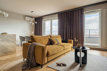 Creative and modern open space interior design with yellow sofa, grey carpet and coffe table . Grey carpet on the herringbone parquet with coffe table, brown curtain in windows. Template. .