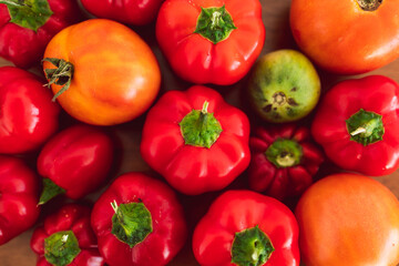 freshly picked mini capsicums and tomatoes with vibrant red and orange tones on wooden tray, simple ingredients concept