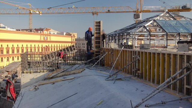 Yellow tower crane. Steel bar rebar metal framework reinforcement for concrete at construction site timelapse. Metal works on a roof of new building in progress with many workers in uniform