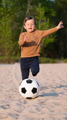 Funny Little Boy Playing with Black and White Soccer Ball in Park on Sand. Kid Running Up to Kick Ball With His Foot