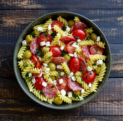 Salad with fusilli pasta, sausage, olives and cottage cheese. Italian food.
