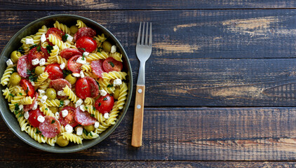 Salad with fusilli pasta, sausage, olives and cottage cheese. Italian food.