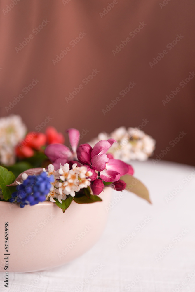 Poster Spring blooming delicate flowers in a round vase on a table with a white tablecloth, a pastel bouquet and a delicate floral card