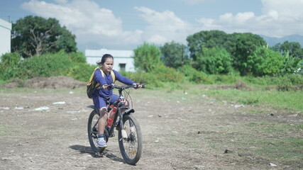 Naklejka premium An Indian Kid cycling on a road, near a sugarcane field in a rural area of Uttarakhand, India. Physical fitness of an Indian boy. High-quality image.