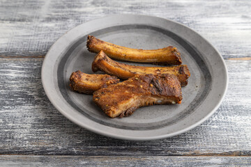 pork ribs on a wooden plate on a gray. Side view.