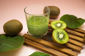 kiwi juice in a glass, kiwi cut in half and kiwi leaves