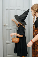 Girl friends in halloween costumes knocking on the door, trick or treating