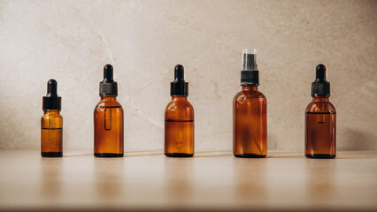 Banner, clear bottles with natural SPA cosmetics on a beige stone background. Front view