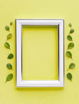 Beautiful flower arrangement. Small green leaves, empty photo frame for text on a 
yellow background. Wedding, birthday. Valentine's Day, mothers Day. top view, copy space