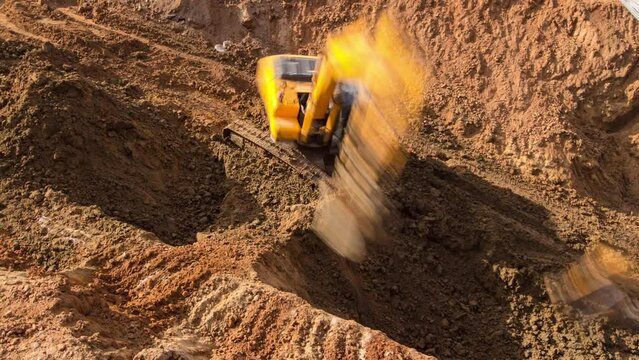 Yellow excavator on a construction site working at huge ditch pit timelapse. Construction site of the underground metro station line. View from above