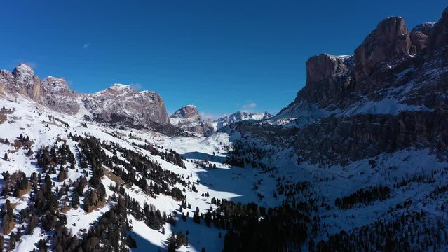 Gardena Pass and Mountains on Sunny Winter Day. South Tyrol, Dolomites, Italy. Aerial View . Drone Flies Backwards