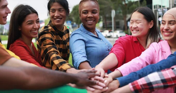 Young multiethnic people having fun stacking hands outdoor 