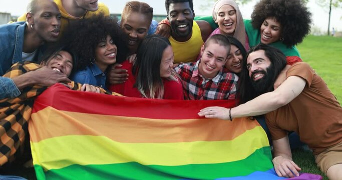 Diverse people having fun holding LGBT rainbow flag outdoor 