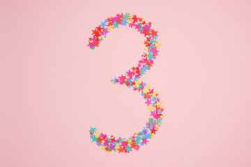Number 3 or three made from decorative multi-colored stars. Holiday numbers or figures. Top view