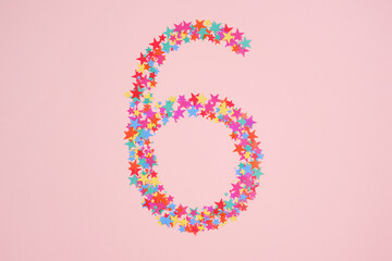 Number 6 made from decorative multi-colored stars. Holiday numbers or figures. Top view