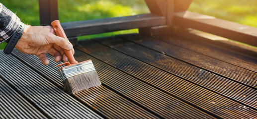 restore wooden terrace planks. applying wood protection oil on boards with paint brush. copy space - obrazy, fototapety, plakaty