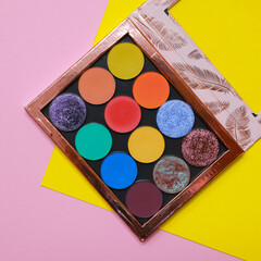 Colorful eyeshadow makeup palette. Realistic image with matte, glitter, multichrome pigments. Shadows set in vibrant colorful scheme. Top view flat lay package isolated on colorful background. - obrazy, fototapety, plakaty