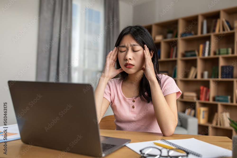 Wall mural Deadline stress. Young korean lady feeling tired after working on laptop, having headache and touching temples