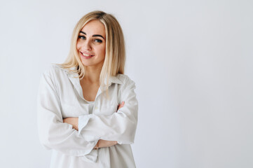 The fair-haired girl smiles broadly with her arms folded across her chest.